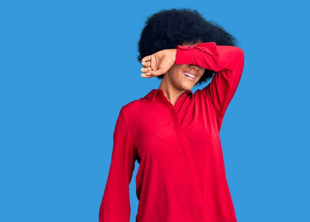 Mladá afroameričanka v neformálním oblečení zakrývajícím oči s veselým a legračním úsměvem na tváři. slepý koncept.  - Fotografie, Obrázek