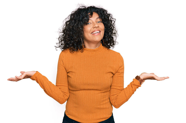 Jeune femme hispanique portant des vêtements décontractés souriant montrant les paumes ouvertes des deux mains, présentant et comparant la publicité et l'équilibre  - Photo, image