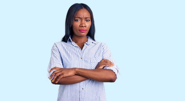 Νεαρή Αφροαμερικανή που φοράει καθημερινά ρούχα σκεπτική και νευρική, αποδοκιμάζει την έκφραση στο πρόσωπο με σταυρωμένα χέρια. αρνητικό πρόσωπο.  - Φωτογραφία, εικόνα