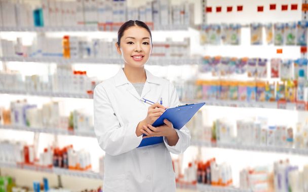 happy asian female pharmacist with clipboard - Foto, immagini