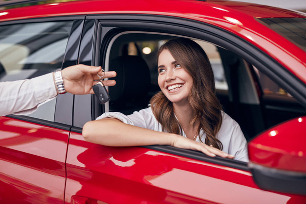 Crop manager giving car key to happy woman - 写真・画像