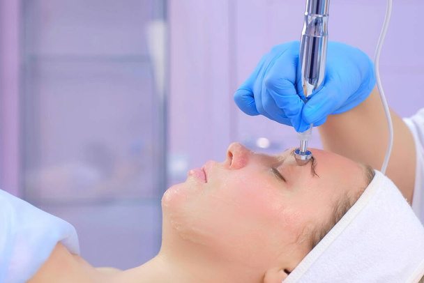 Microcurrent face treatment with hyaluronic acid gel for young woman, closeup. - Foto, Bild