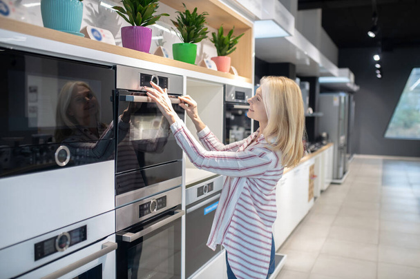 Blonde customer choosing oven in a showroom - Foto, afbeelding