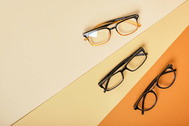 several pairs of glasses on beige and brown background, geometric background top view copy space - Foto, Imagen