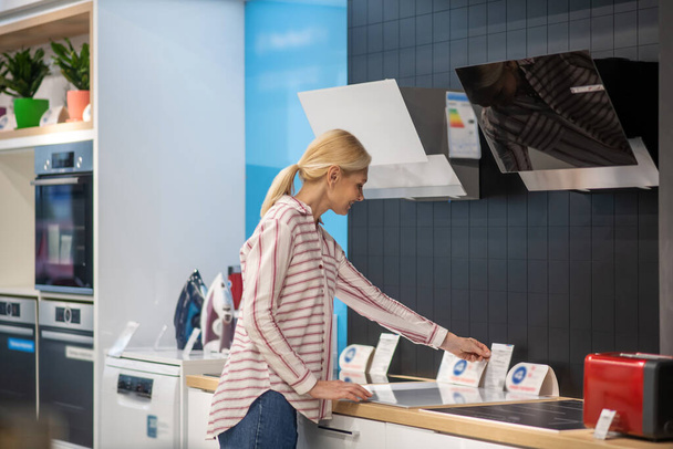 Blonde female customer choosing goods in a showroom - Фото, зображення