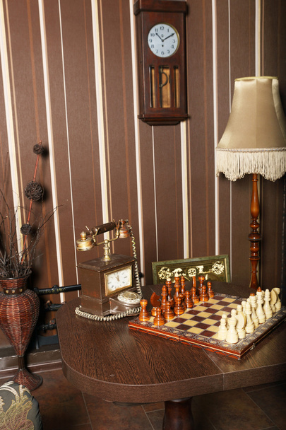 Interior da sala retro com relógio de parede de pêndulo de xadrez de madeira e telefone de discagem
 - Foto, Imagem