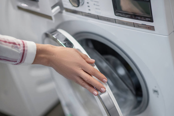 Close up picture of womans hands examining a washing machine - Foto, Imagen
