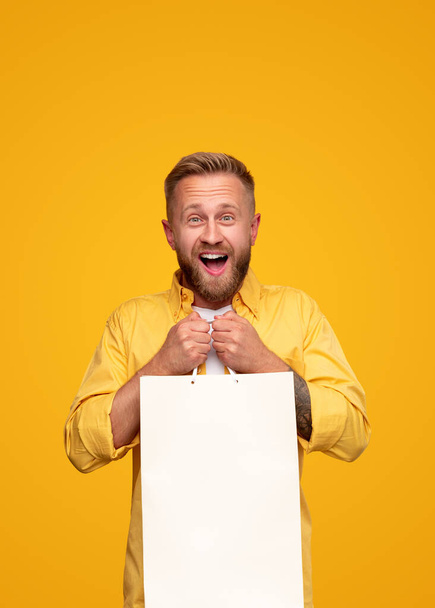 Excited bright man with blank paper bag - Photo, Image