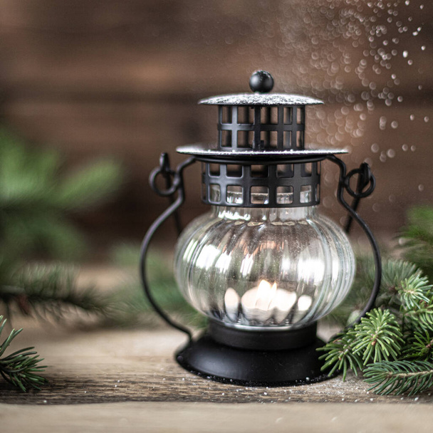 Christmas lantern with a candle and fir branches with cones on a wooden table, copy space - Foto, Imagem