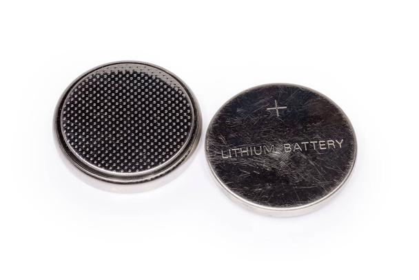 Zwei gebrauchte Lithium-Knopf-Akkus liegen mit unterschiedlichen Anschlüssen auf weißem Hintergrund in Großaufnahme - Foto, Bild