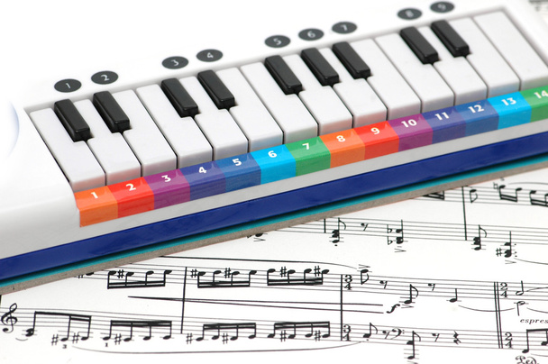 σημειώσεις και πιάνο με αριθμημένες πολύχρωμα πλήκτρα - Φωτογραφία, εικόνα
