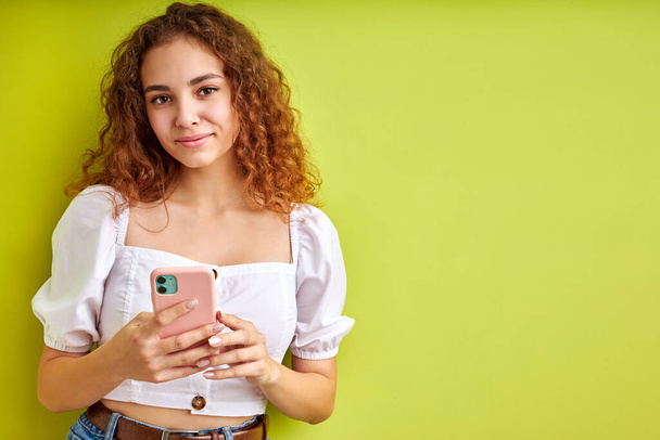 cute curly teen girl enjoy chatting with someone using mobile phone - Zdjęcie, obraz