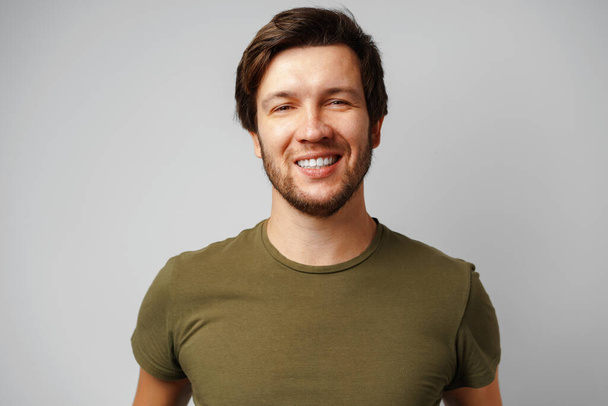 Handsome young man portrait smiling against grey background - Photo, image