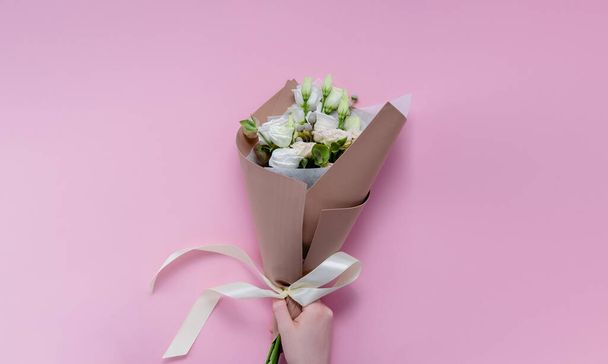 Female hands florist making a bouquet. Step by step instraction. Top horizontal view copyspace pink background - Foto, imagen