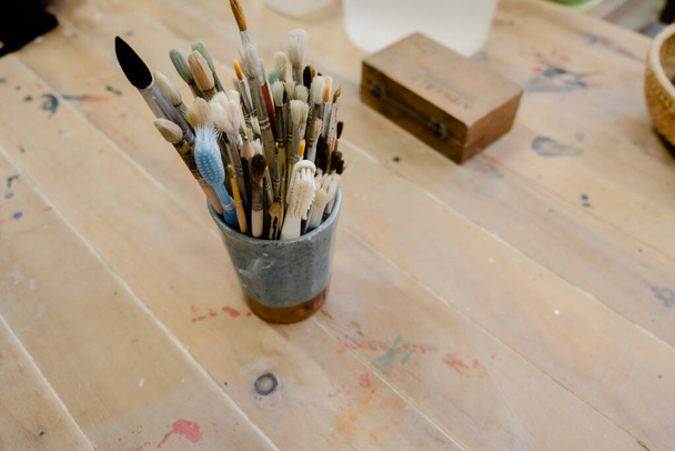 Set de pinceles de arte usados sobre fondo de madera clara, vista superior con espacio para copiar. Arte creativo y concepto de dibujo . - Foto, imagen