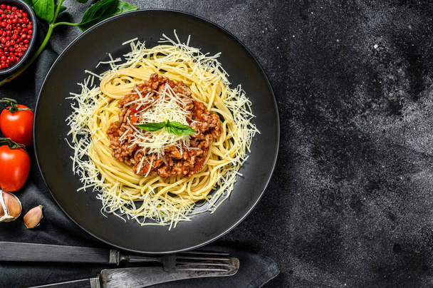 Italialaista spagettipastaa tomaattikastikkeella, juustoparmesaanilla ja basilikalla. Musta tausta. Huippunäkymä. Kopioi tila. - Valokuva, kuva