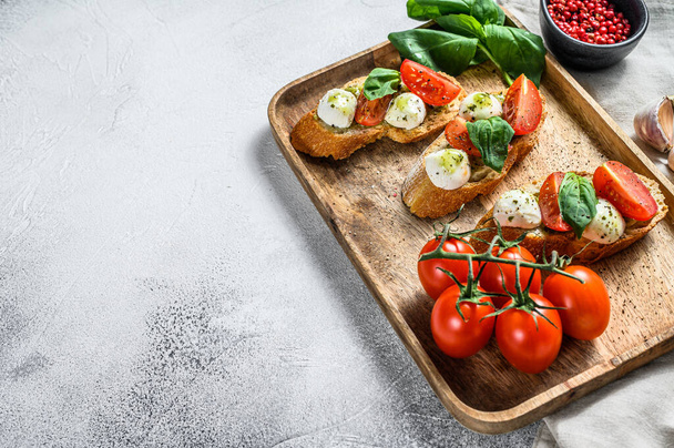 Bruschetta with tomatoes, mozzarella cheese and basil. italian appetizer or snack, antipasto. gray background. top view. Copy space. - Photo, image