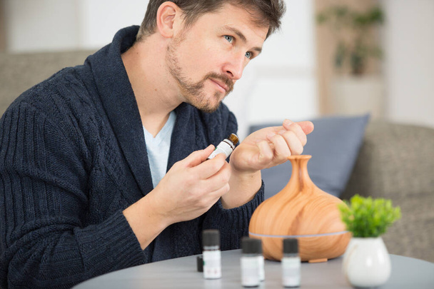 man with diffuser smelling aromatherapy oils - Fotó, kép