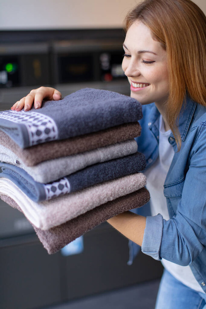 confident woman holding clean towels after laundry - Photo, Image