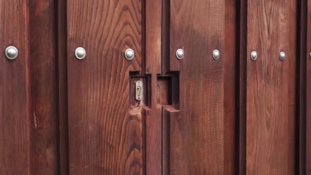 Χαραγμένη ξύλινη πύλη με πριτσίνια και κλειδαριά νεκροψίας κοντά - Πλάνα, βίντεο
