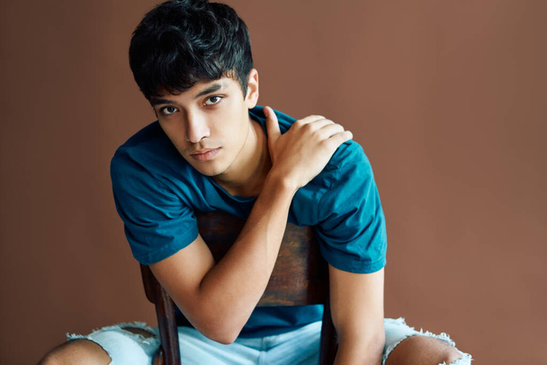 Stylish handsome young man posing on studio sitting on a chair looking to camera - Foto, imagen
