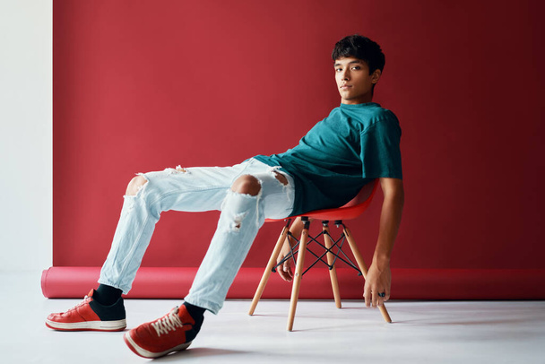 Stylish handsome young man relax and posing on studio sitting on a chair looking to camera. - Photo, image