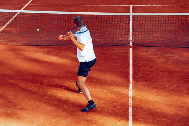 Back view of a man playing tennis on tennis court - Foto, Bild