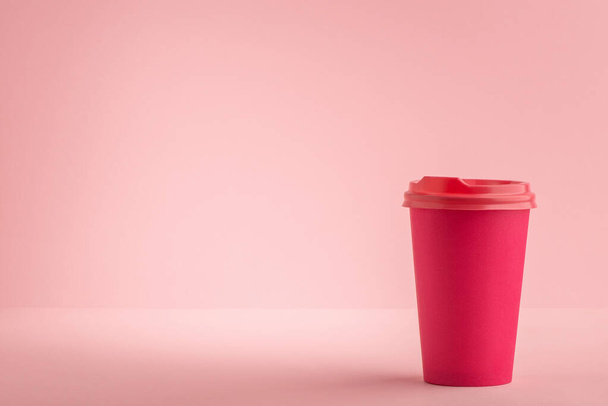 Pink paper cup with plastic lid on light pink background - Fotó, kép