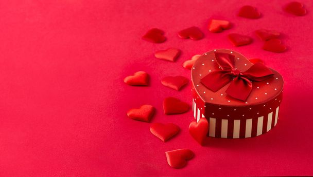 Gift box with heart shape and hearts on red background. Copy space - 写真・画像