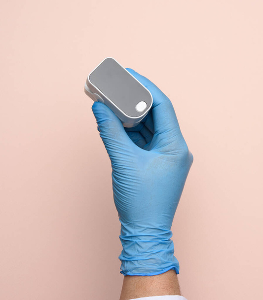 ηλεκτρονικό παλμικό οξύμετρο στα χέρια γιατρού, φορώντας μπλε λατέξ γάντια, κοντινό πλάνο - Φωτογραφία, εικόνα