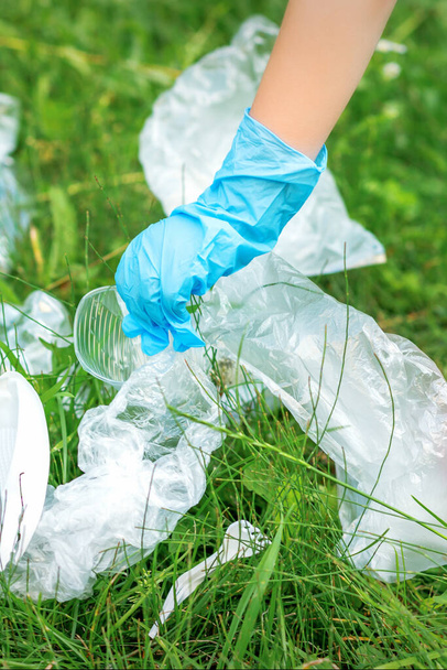 Lapsen käsi puhdistaa puiston muovi astiat ruoho puistossa - Valokuva, kuva