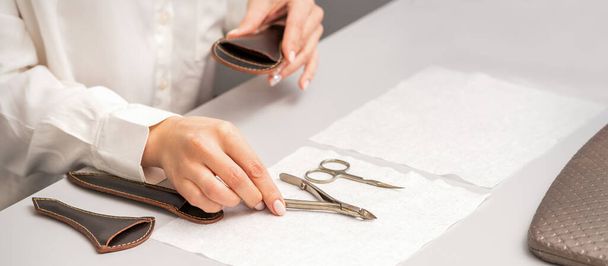 Manicurist's hands lay down manicure tools on table preparing for manicure procedures - Фото, изображение