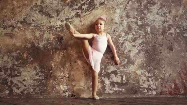 La gimnasta infantil levanta un pie en las divisiones. Deportes infantiles. flexibilidad y estiramiento.  - Metraje, vídeo