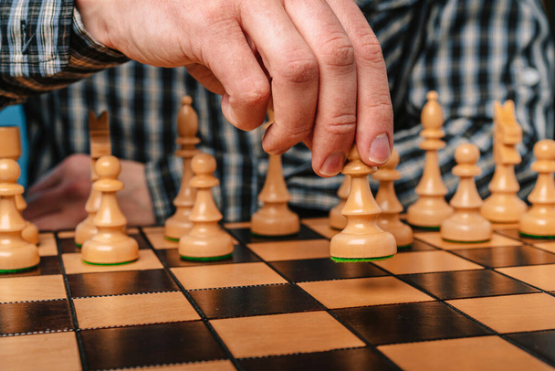 Człowiek w koszuli w kratę porusza figurą szachową, koncepcją strategii i przywództwa - Zdjęcie, obraz