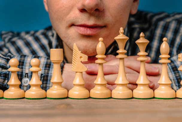 Un homme en chemise à carreaux penché sur une rangée de pièces d'échecs - Photo, image