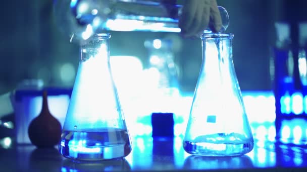 Científico en laboratorio haciendo experimento químico con líquido en frascos - Imágenes, Vídeo