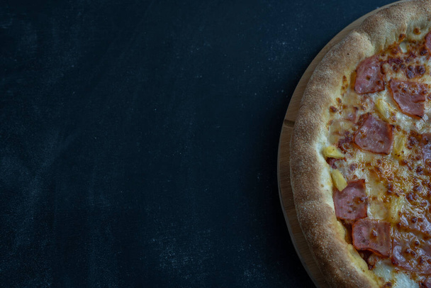 Havaijilainen pizza juustolla, rapealla pekonilla ja ananaksella tummalla taustalla kopiointitilalla . - Valokuva, kuva
