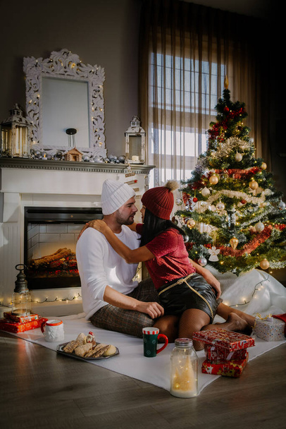 Family sitting on a floor. Couple near christmas tree, Christmas couple with present - Foto, afbeelding