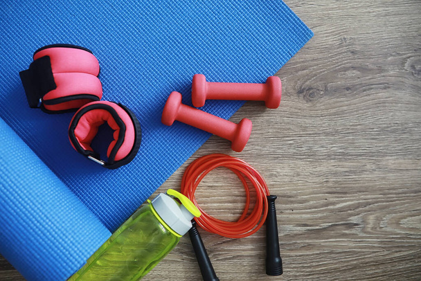 Sport and healthy lifestyle. Accessories for sports. Yoga mat dumbbell and jump rope. Sports background with home exercises concept. - Foto, Imagen