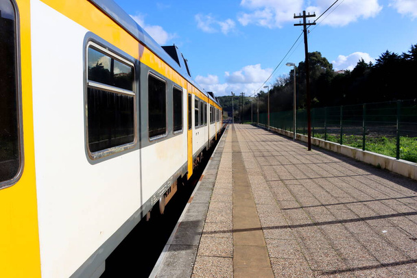 Ein Zug steht auf dem Bahnsteig vor blauem Himmel. Der Zug verlässt den Bahnhof Torres Vedras in Portugal. - Foto, Bild