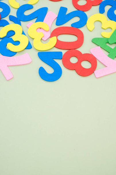 A closeup of the colorful wooden numbers scattered on a green surface - space for text - Foto, immagini