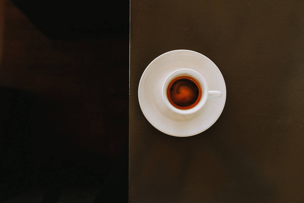 A top view of a cup filled with hot coffee on a table - Фото, зображення
