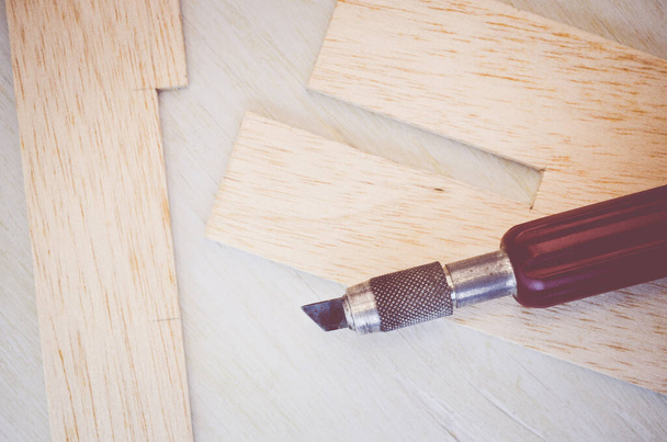 Un primer plano de hoja de madera de balsa y cuchillo de corte sobre un fondo de madera - Foto, Imagen