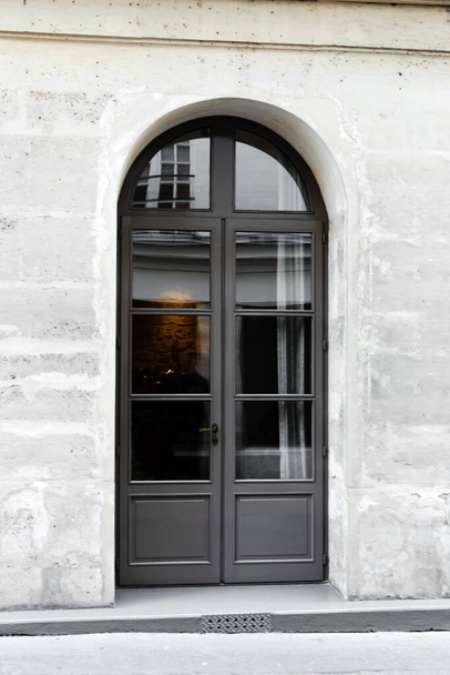 New arched gray wooden double leaf door. Wooden gate - entrance. Vintage old gray door in stone wall in concrete house Paris France - Фото, изображение