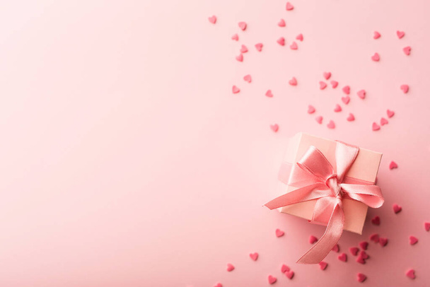 gift and small hearts on pink background with copy space. - Foto, Imagem