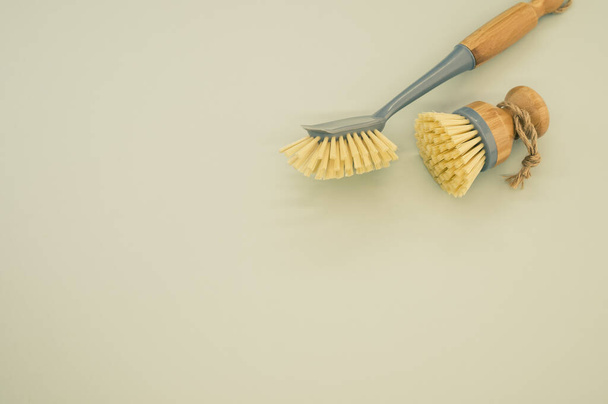 A closeup of a set of wooden dishwashing brushes on a green surface - space for text - Фото, изображение
