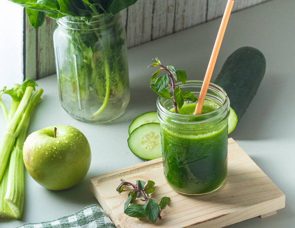 A closeup shot of a green smoothie with cucumber and apples - Fotó, kép