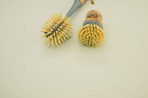 A closeup of a set of wooden dishwashing brushes on a green surface - space for text - Photo, image