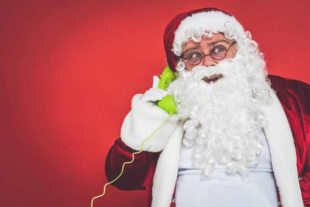 Funny crazy santa claus having fun on a red colored background - 写真・画像
