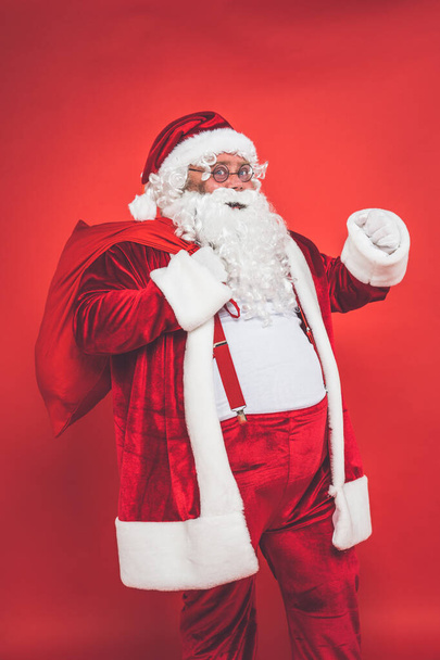 Funny crazy santa claus having fun on a red colored background - Foto, Imagen
